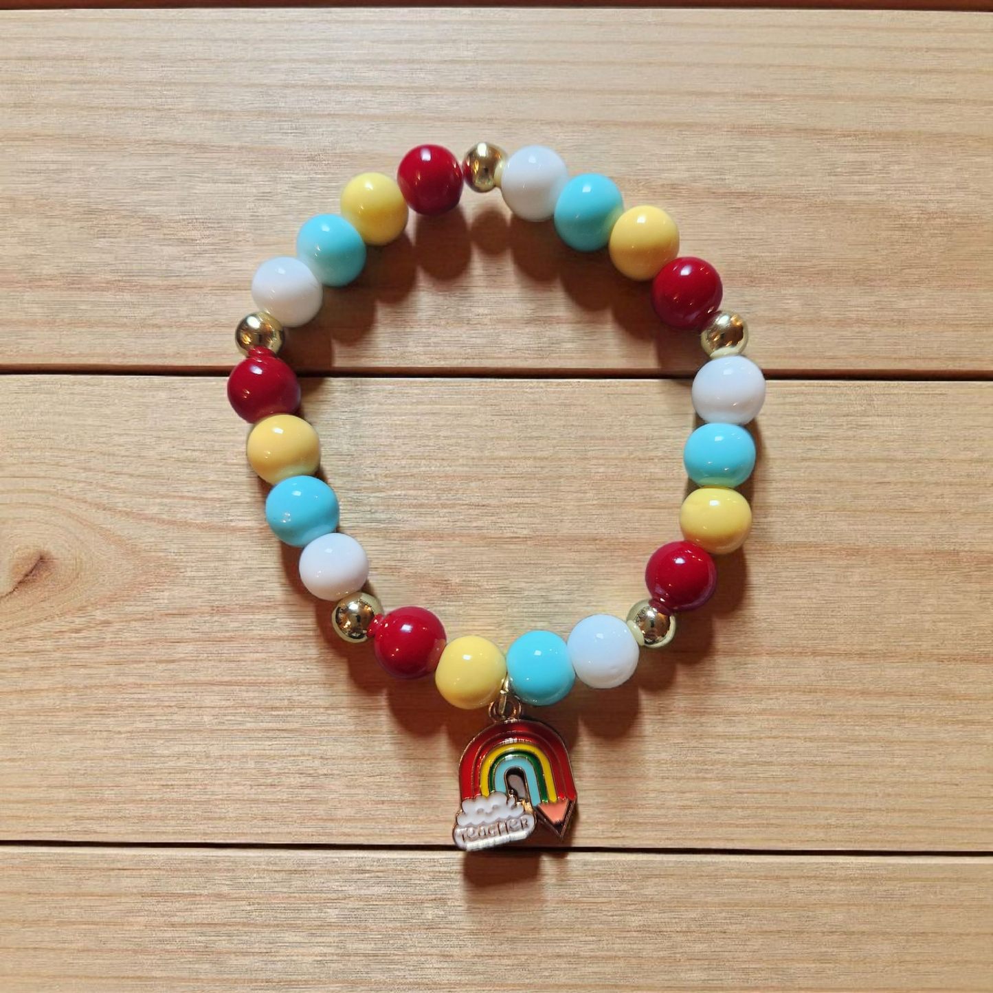 Colorful beaded bracelet with a rainbow charm on a wooden surface
