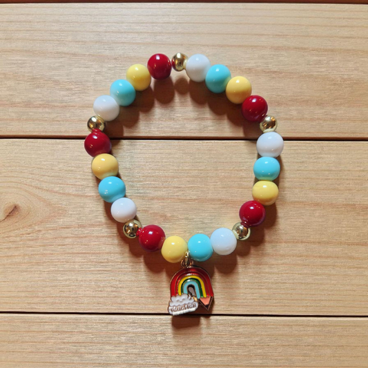 Colorful beaded bracelet with a rainbow charm on a wooden surface