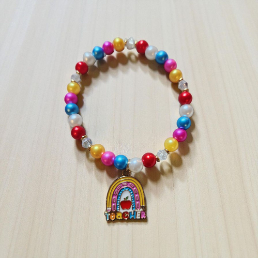 Colorful beaded bracelet with a rainbow charm and 'Teacher' text on a light wooden surface